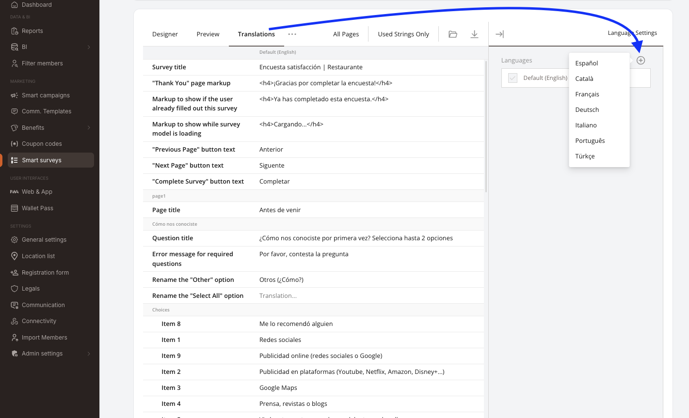 La pestaña Translations del constructor de encuestas. Barra de pestañas: Designer / Preview / Translations, con los filtros All Pages y Used Strings Only e iconos de importar / exportar. La tabla lista a la izquierda cada texto traducible (Survey title, markup de la página "Thank You", texto de los botones Previous / Next / Complete, títulos de página, títulos de pregunta, mensajes de error, opciones de respuesta) con la columna Default (English) rellenada en español. A la derecha, el panel Language Settings lista los idiomas ya añadidos, con un botón + que abre un desplegable de idiomas disponibles: Español, Català, Français, Deutsch, Italiano, Português, Türkçe.