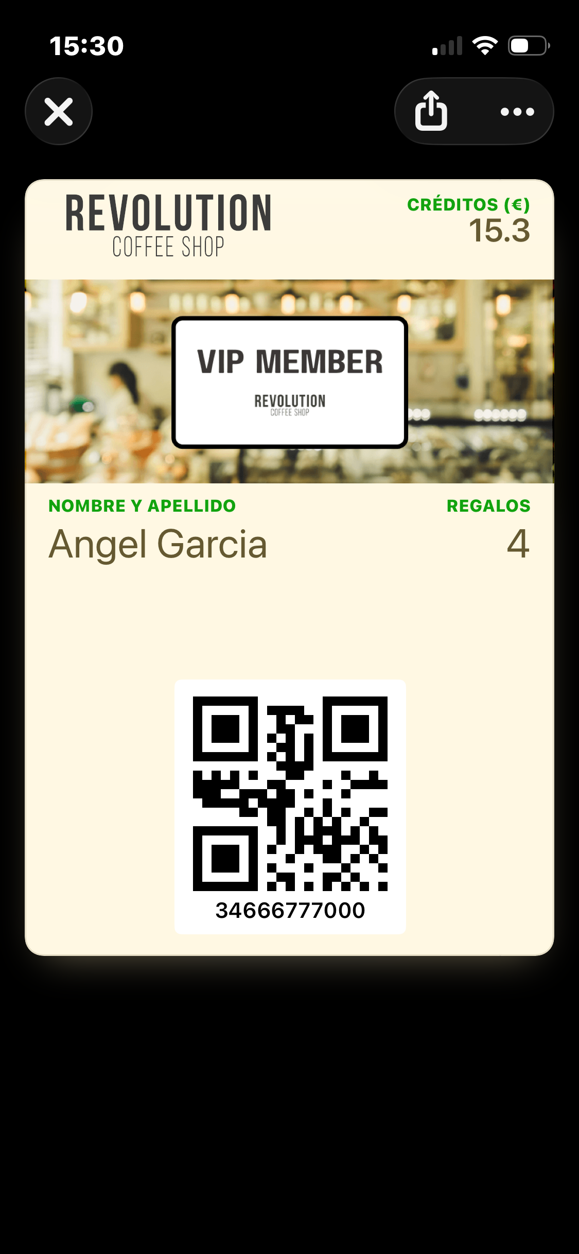 Nivel_VIP etiketli bir üye için iPhone'da koşullu görünümlü Wallet Pass — sol üstte Revolution Coffee Shop yazı işareti, sağ üstte Créditos (€) 15.3, VIP MEMBER strip görseli, yeşil etiket renkleri ve koyu kahverengi metin bulunan krem renkli kart, altta üye QR'ı ve kimliği. Varsayılan pasoyla aynı veriler, sadece farklı bir görsel işlem